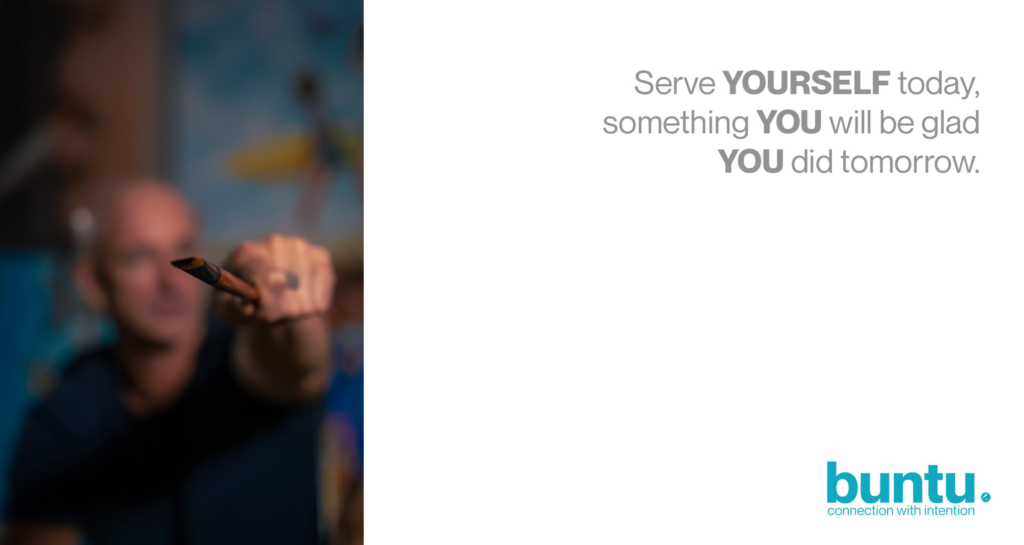 : The image is a split composition with a blurred, dark background photo on the left and a white background with text on the right. The left side shows a person, out of focus, extending an object that looks like a paintbrush towards the viewer. The right side features grey text that reads: "Serve YOURSELF today, something YOU will be glad YOU did tomorrow." In the bottom right corner, the "buntu." logo is displayed in blue text with "connection with intention" below it.
